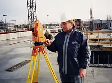 Vermesser mit Messgerät auf einer Baustelle